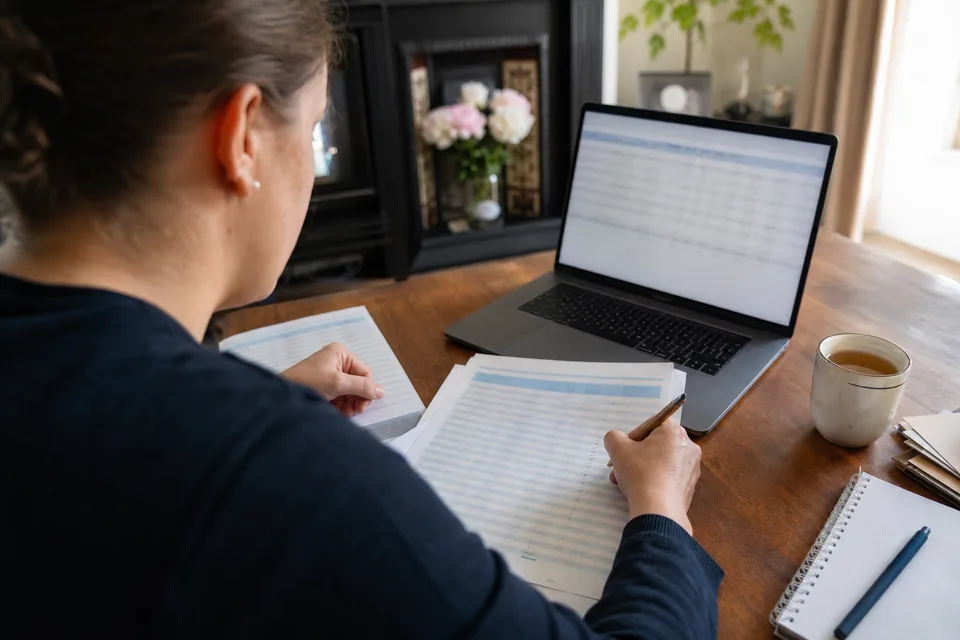 Bookkeeper reviewing bank transactions on a laptop next to a ticked statement