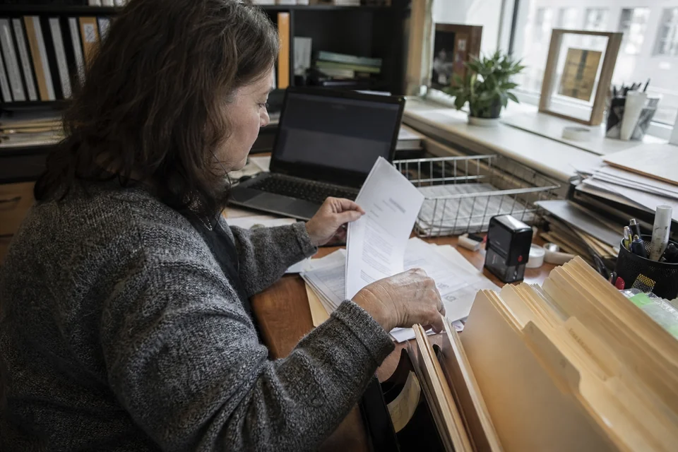 Bookkeeper sorting printed monthly bank statements into client folders