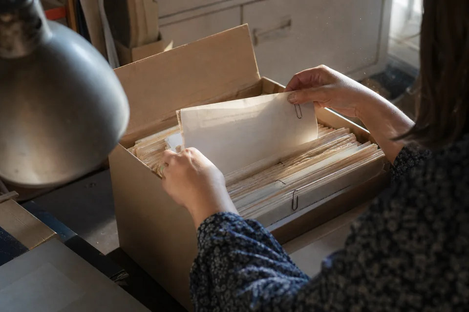 Archive box of older paper bank statements being sorted