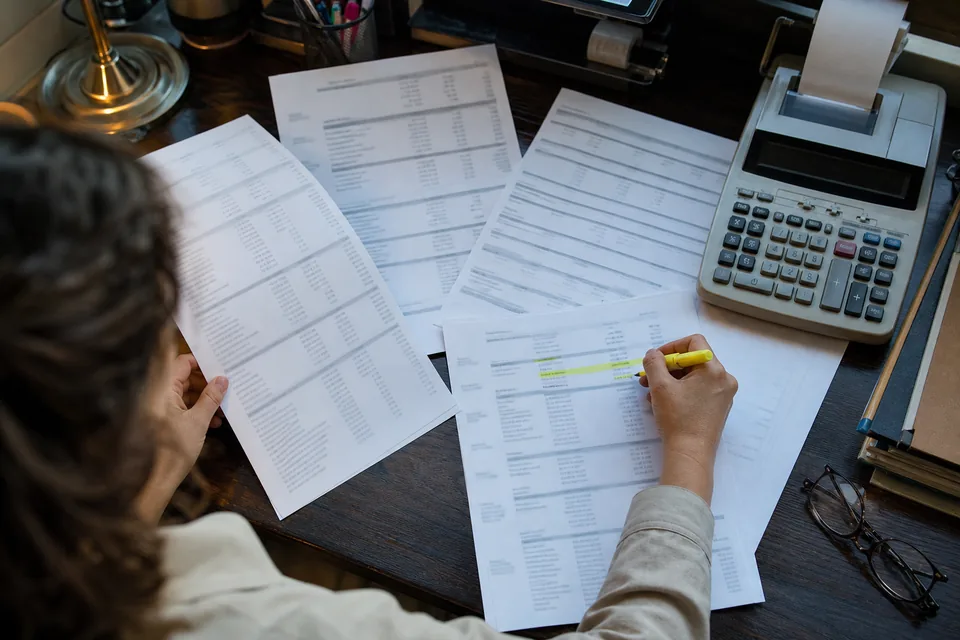 Printed statement pages with a highlighter marking rows to review on a loan processor's desk