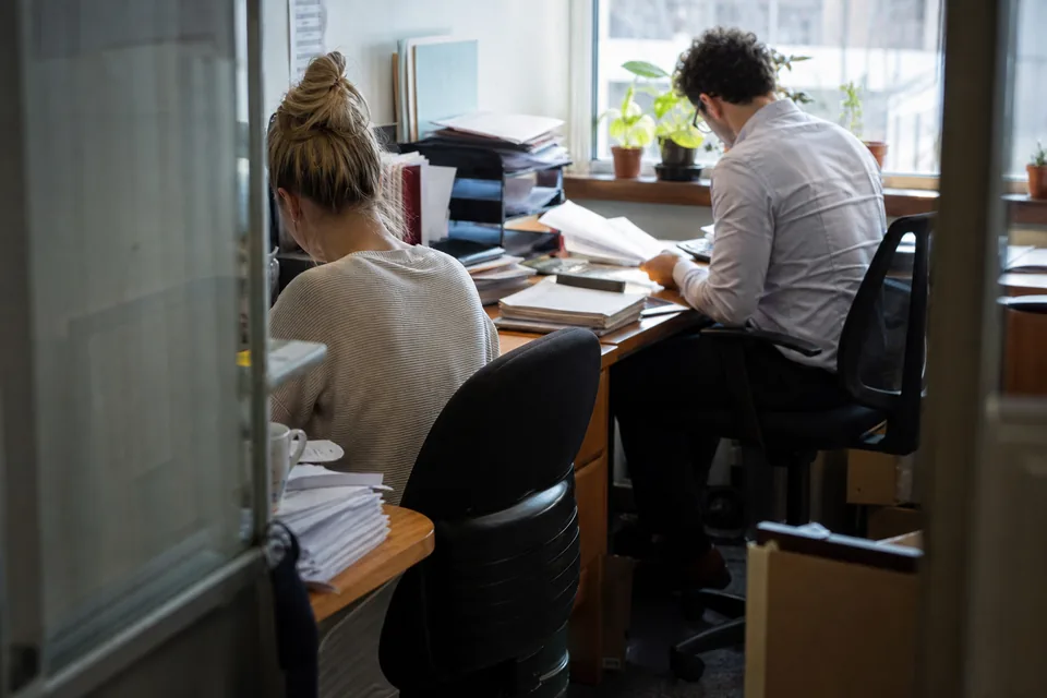 Small bookkeeping office with stacks of client statements on two desks